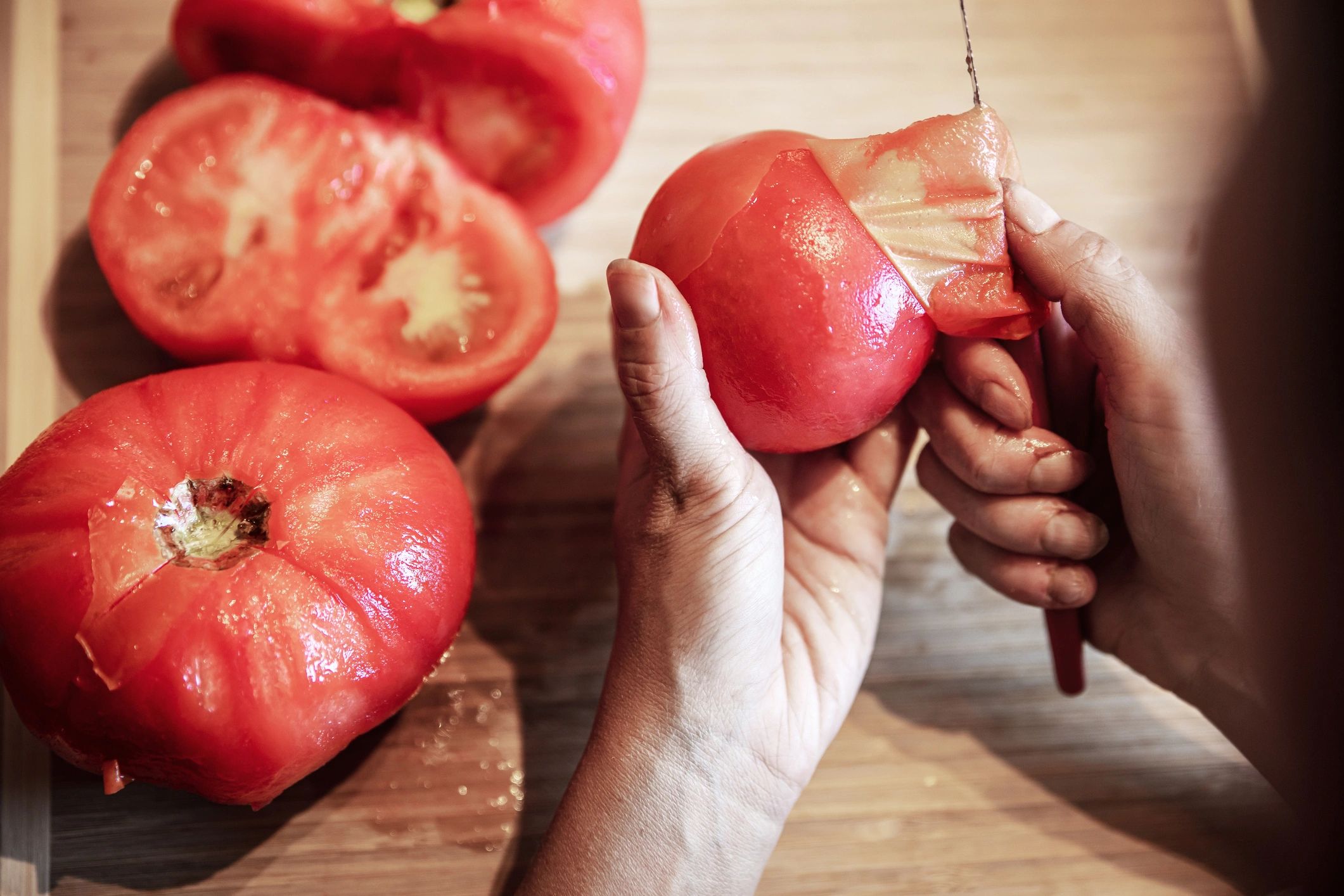 Person peeling tomatoes in preparation for cooking